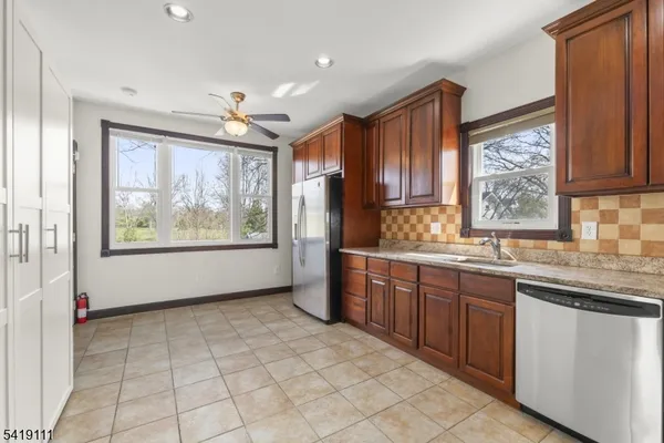 a kitchen with stainless steel appliances granite countertop a refrigerator sink and wooden cabinets