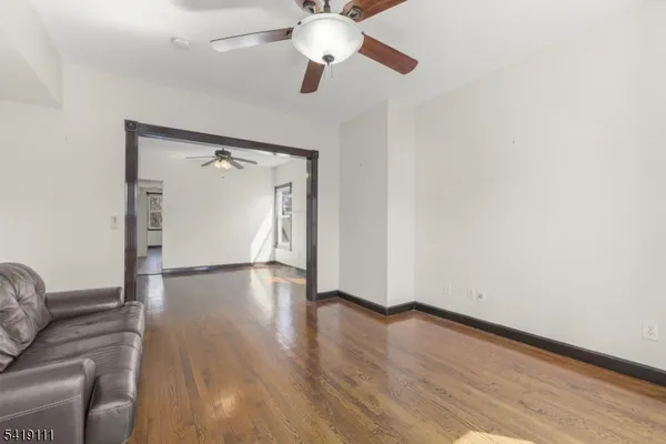 a view of empty room with wooden floor and fan