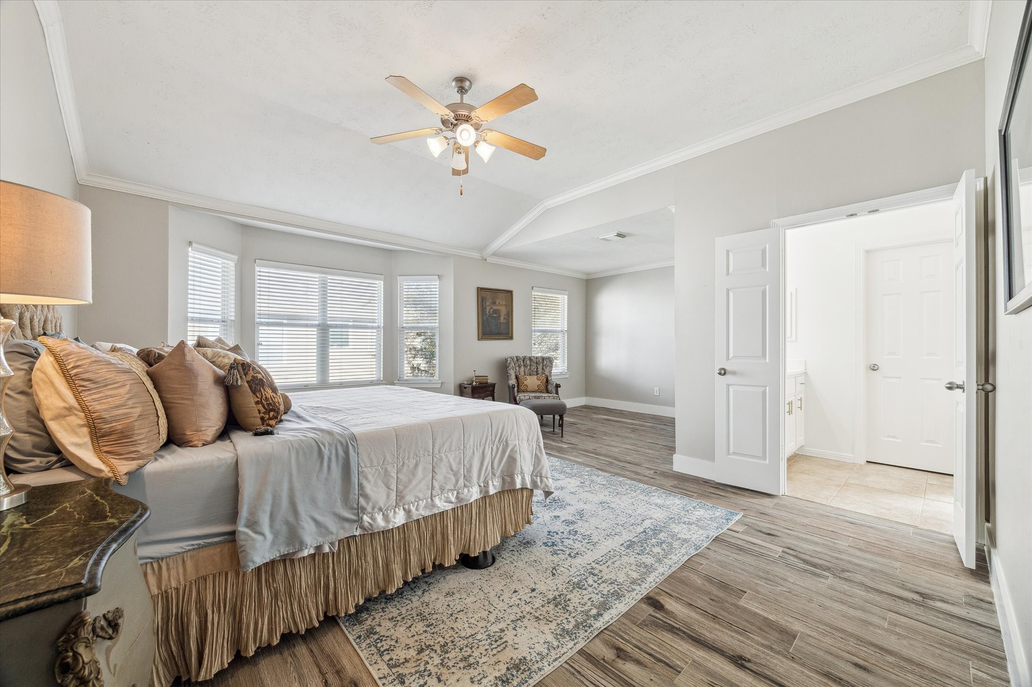 5242 Eigel Street Houston, TX 77007 - Photo 16 of 29 Spacious and bright primary bedroom with large windows, wood flooring, and neutral tones. Features a ceiling fan, elegant decor, and an en-suite bathroom.