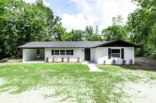 a front view of a house with a garden and trees