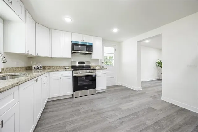 a kitchen with granite countertop a refrigerator and a stove top oven