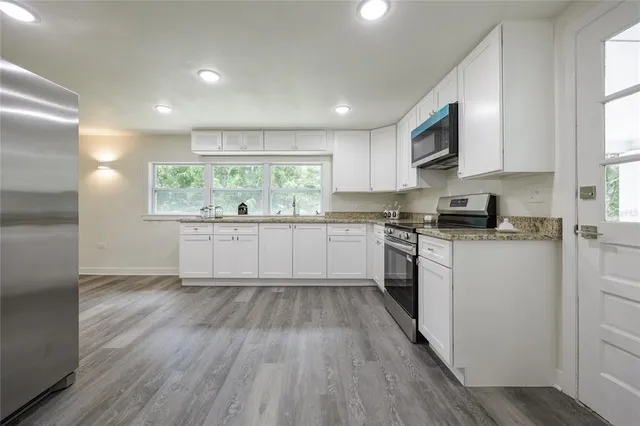 a kitchen with a sink wooden floor cabinets and a window