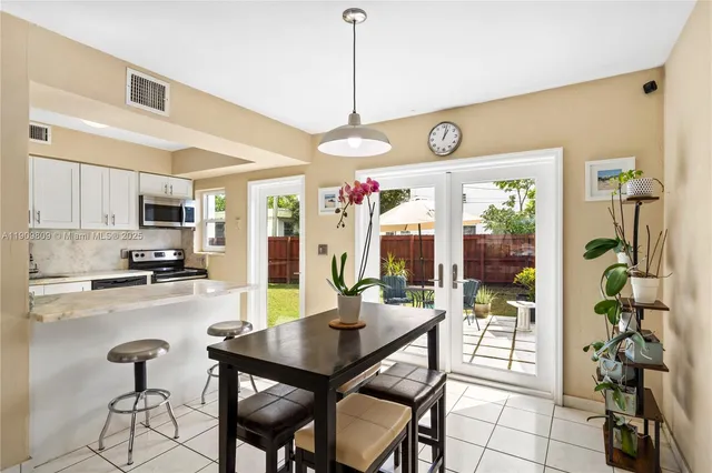 a kitchen with stainless steel appliances granite countertop a stove a refrigerator a sink a dining table and chairs with wooden floor