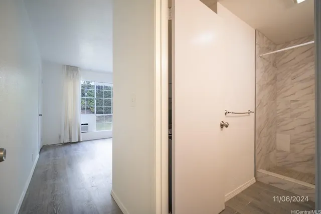 a view of a hallway with wooden floor and a bathroom