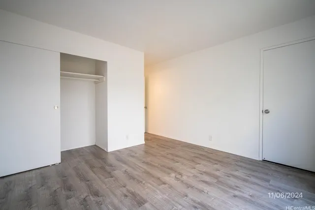 a view of an empty room with wooden floor and closet