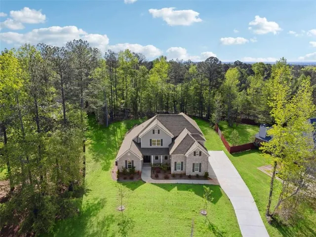 an aerial view of a house with a big yard and large trees
