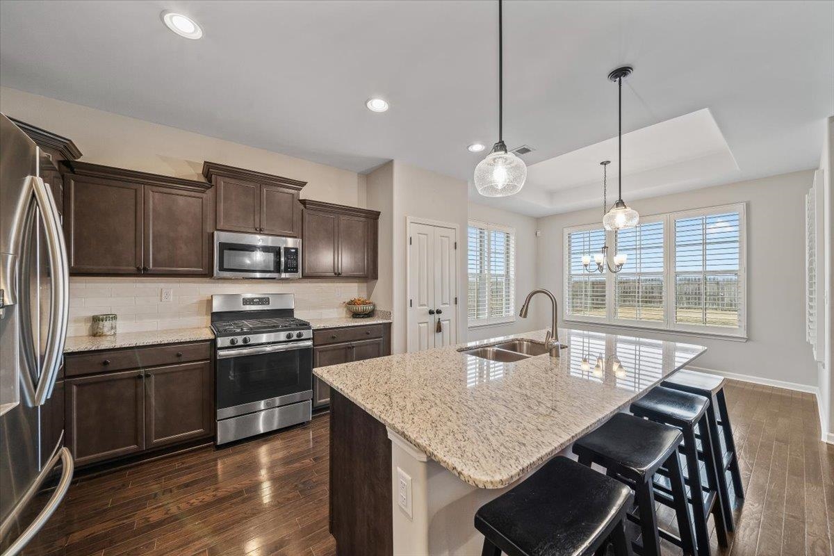 55 Cypress Point Road Oakland, TN 38060 - Photo 10 of 32 a kitchen with stainless steel appliances granite countertop a kitchen island hardwood floor sink stove dining table and chairs