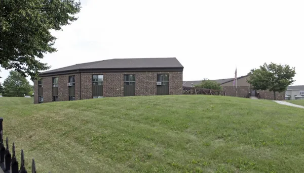 a brick house with a big yard and large trees