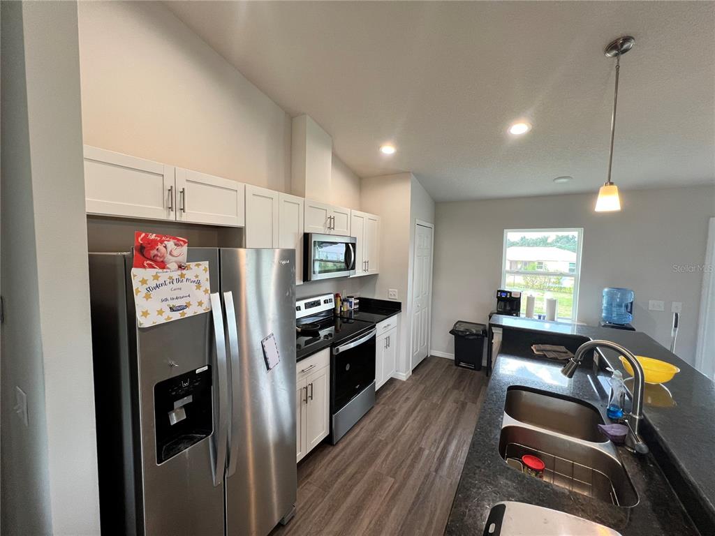 4264 East Taper Street Inverness, FL 34453 - Photo 18 of 29 a kitchen with stainless steel appliances kitchen island granite countertop a refrigerator a sink dishwasher a dining table and chairs with wooden floor
