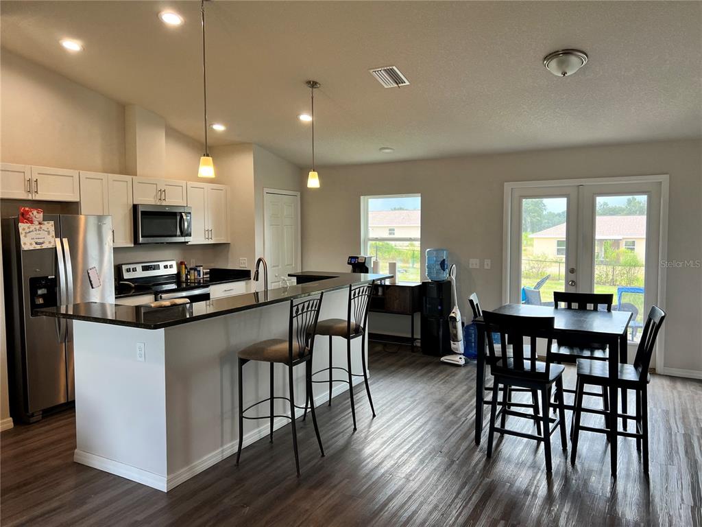 4264 East Taper Street Inverness, FL 34453 - Photo 24 of 29 a kitchen with stainless steel appliances granite countertop a stove a refrigerator a kitchen island a dining table and chairs with wooden floor