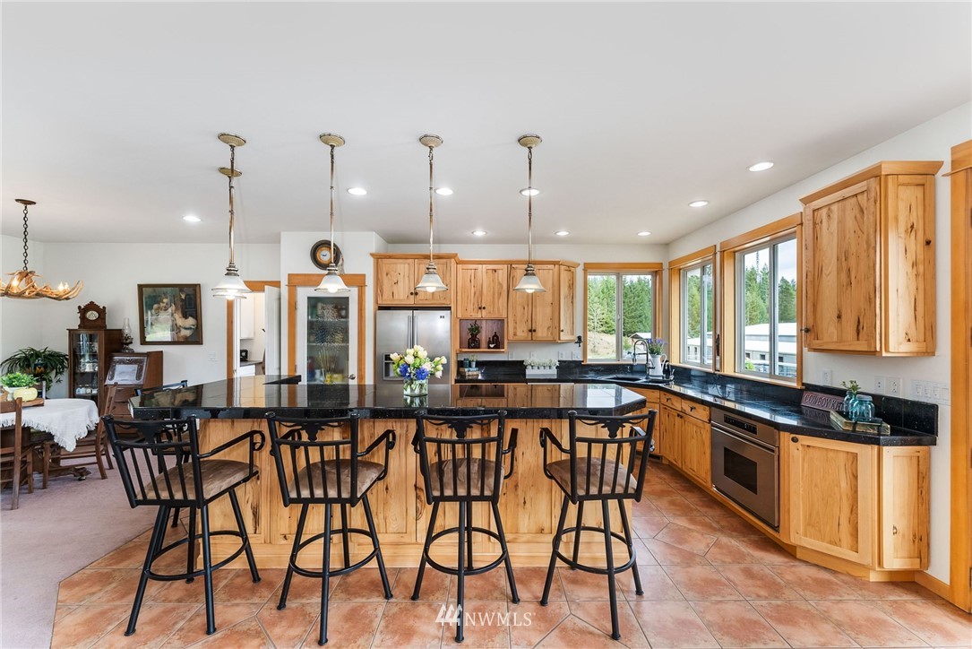 1579 Southwest J H Road Port Orchard, WA 98367 - Photo 7 of 36 a kitchen with stainless steel appliances kitchen island granite countertop a table chairs sink and cabinets