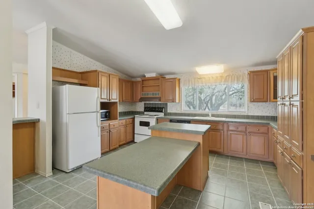 a kitchen with kitchen island granite countertop a refrigerator and a sink