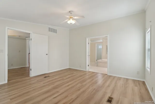 a view of empty room with wooden floor and fan