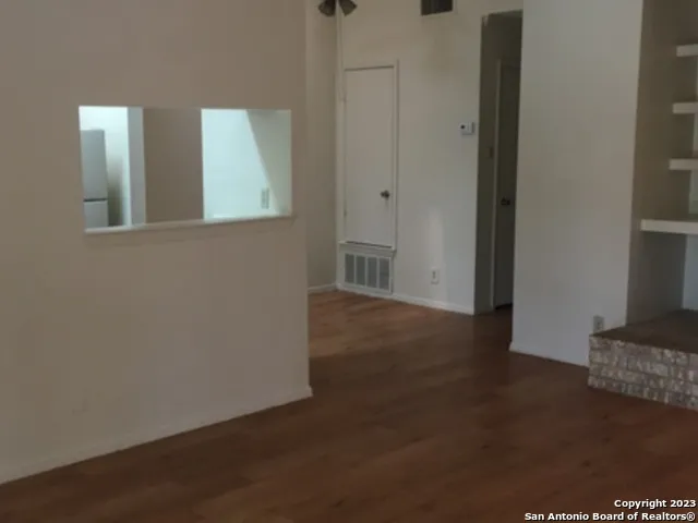 a view of an empty room with wooden floor and a cabinet
