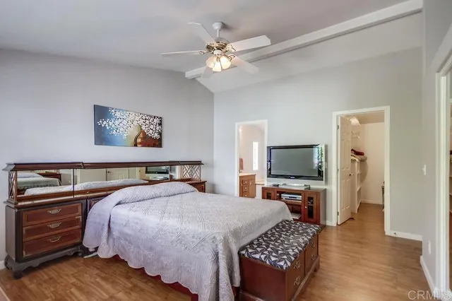 a bedroom with a bed a dresser and wooden floor