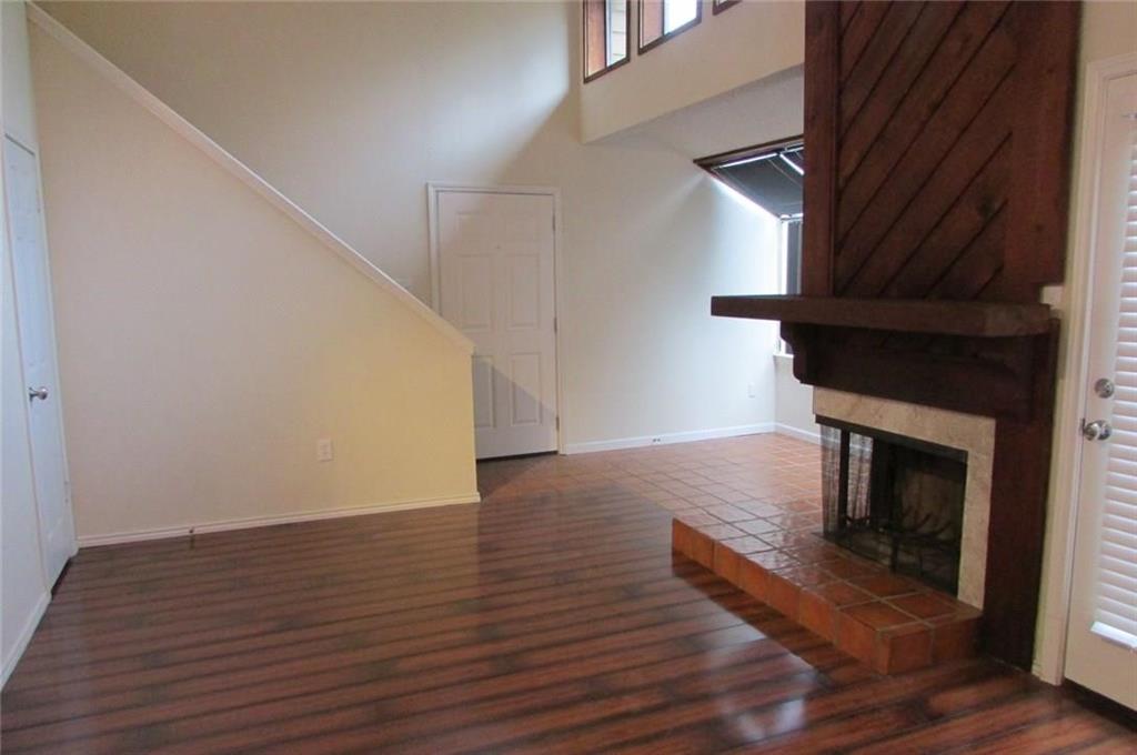 9254 Forest Lane, Unit 304 Dallas, TX 75243 - Photo 4 of 17 a view of an empty room with wooden floor and a fireplace