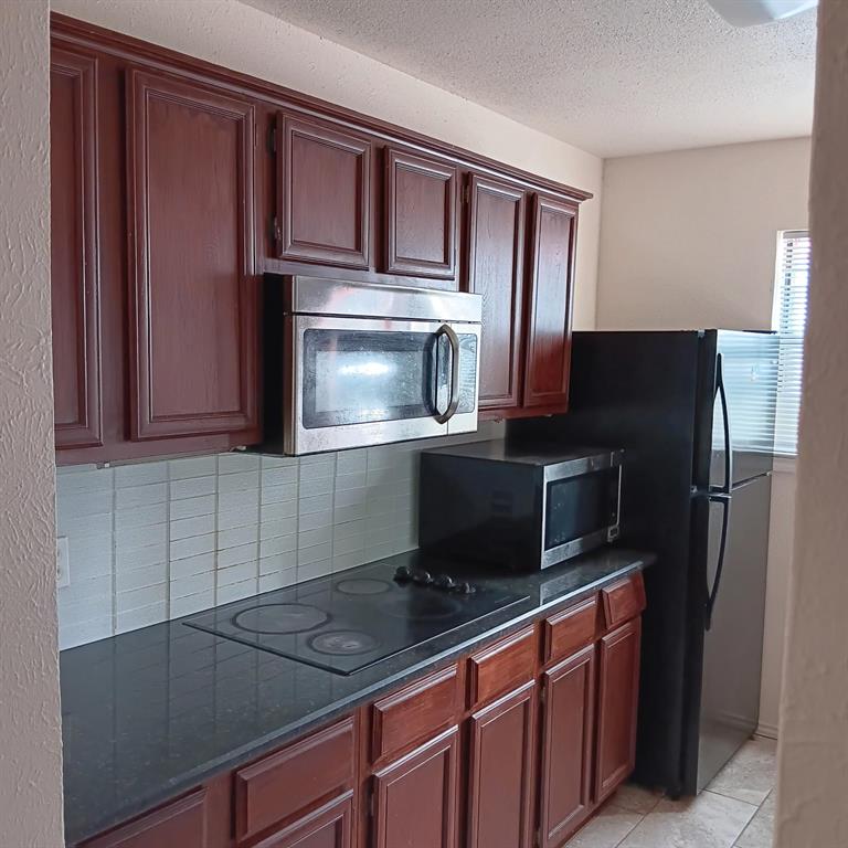 9254 Forest Lane, Unit 304 Dallas, TX 75243 - Photo 7 of 17 a kitchen with granite countertop stainless steel appliances and wooden cabinets