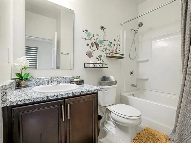 a bathroom with a granite countertop sink a toilet and shower