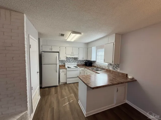 a kitchen with a sink a refrigerator and white cabinets