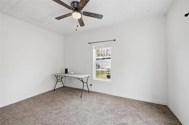 an empty room with a window and a fan