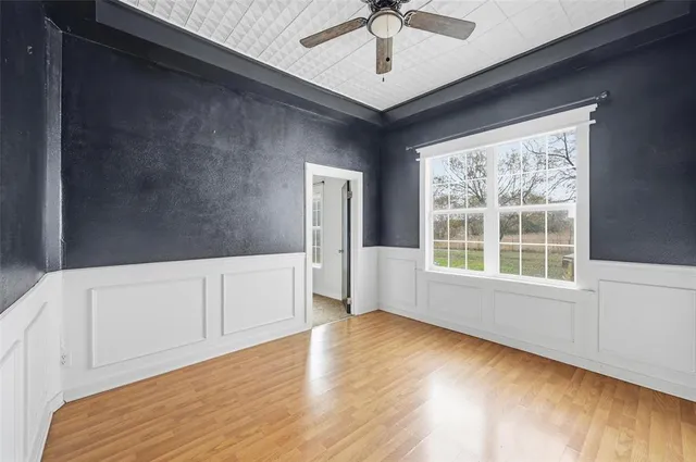a view of an empty room with a window and wooden floor