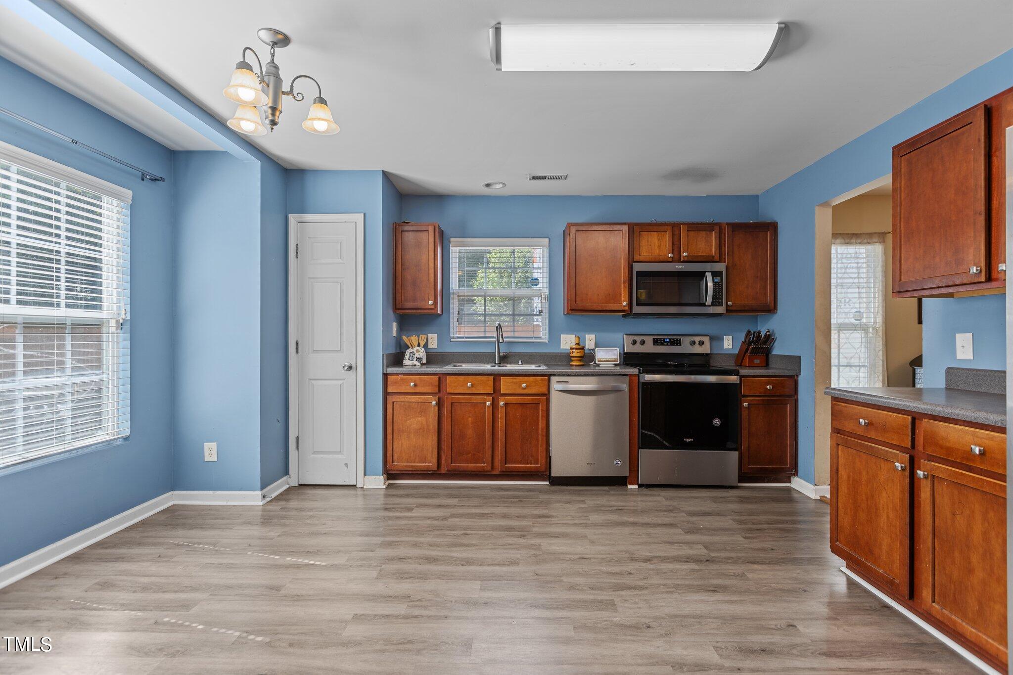 4232 Dalcross Road Raleigh, NC 27610 - Photo 11 of 38 a kitchen with stainless steel appliances granite countertop a stove top oven a sink dishwasher a refrigerator and a microwave oven with wooden floor