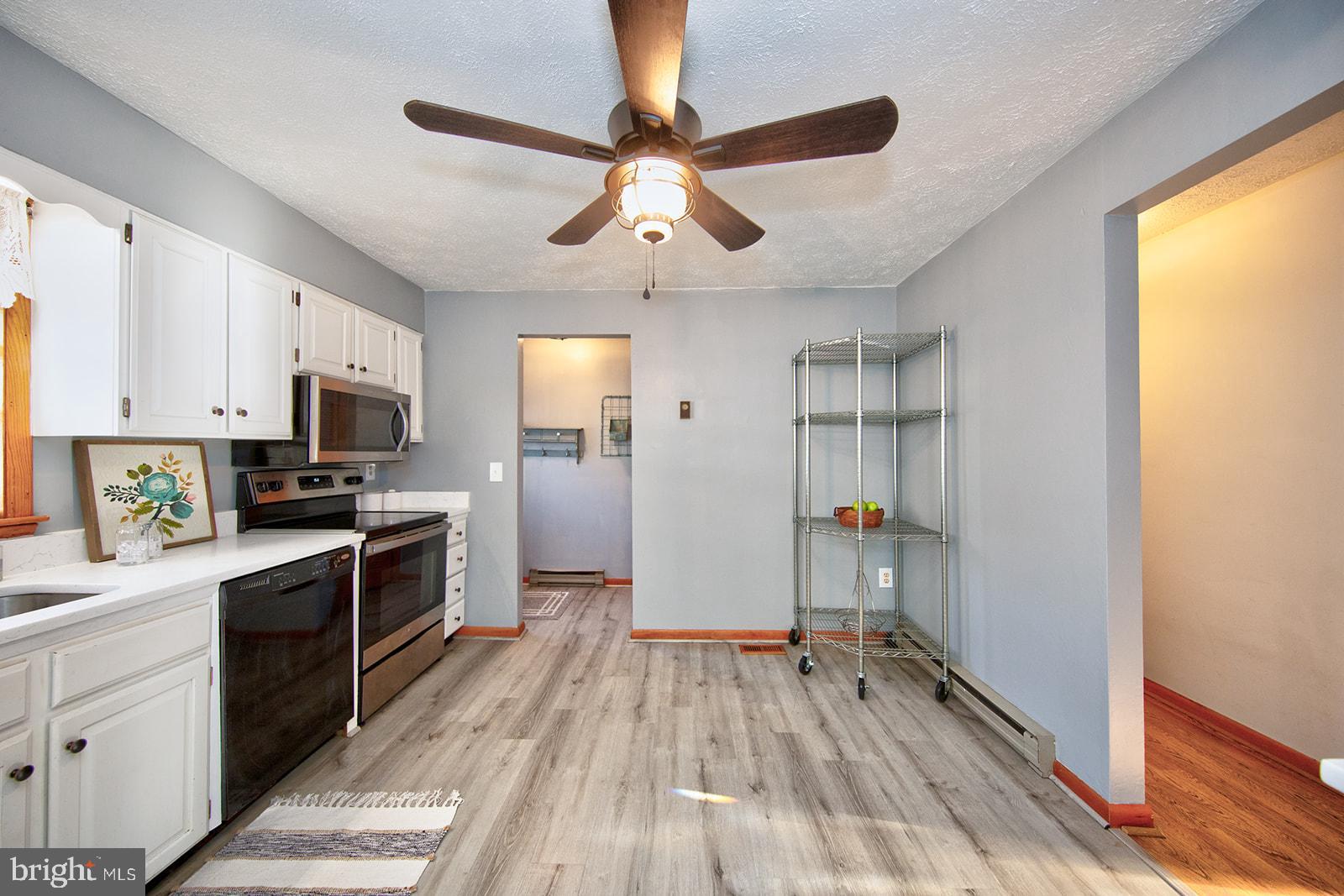 13202 Cherwin Avenue Baltimore, MD 21220 - Photo 16 of 49 a kitchen with granite countertop a refrigerator oven a sink dishwasher and white cabinets with wooden floor