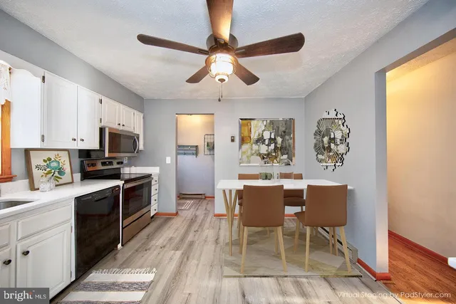 a kitchen with granite countertop stainless steel appliances a dining table and chairs