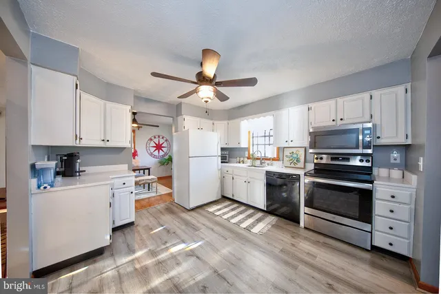 a kitchen with granite countertop a sink cabinets and stainless steel appliances