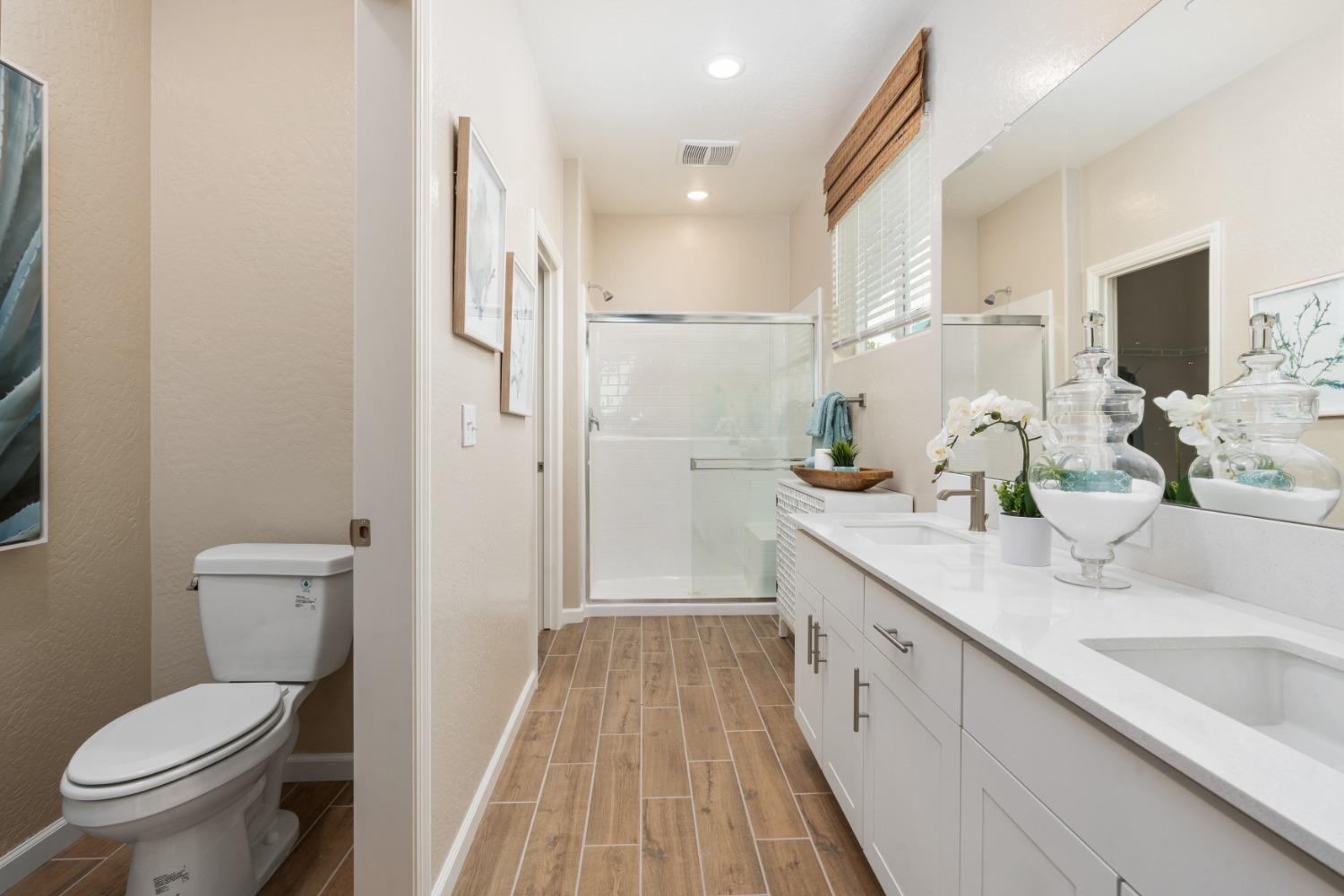 1167 Elevations Way West Madera, CA 93636 - Photo 22 of 28 a spacious bathroom with a sink a toilet a mirror and shower