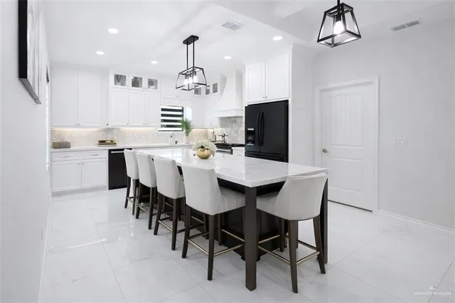 a kitchen with kitchen island a dining table chairs stainless steel appliances and cabinets
