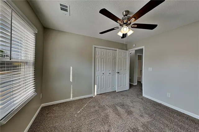 a view of an empty room with window and ceiling fan