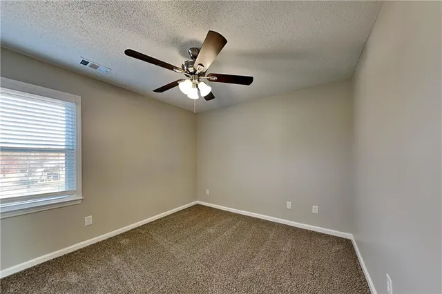 an empty room with a window and a ceiling fan