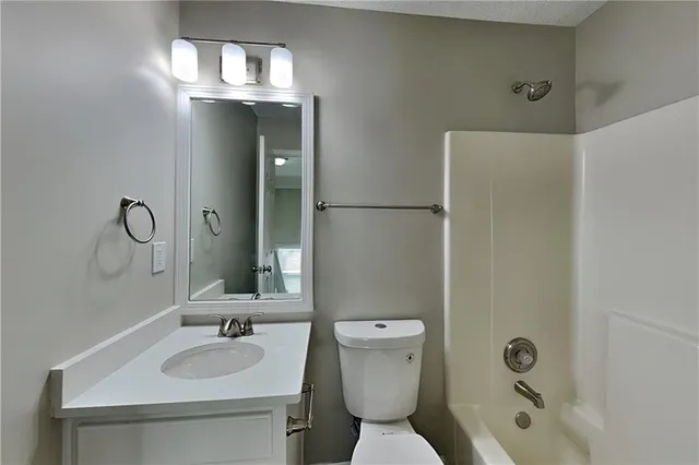 a bathroom with a granite countertop sink toilet and mirror