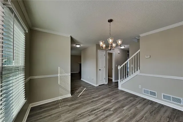 a view of a hallway with wooden floor and chandelier