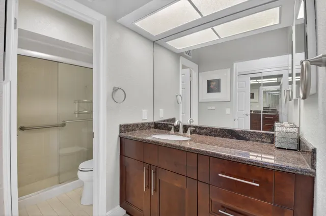 a bathroom with a granite countertop sink a toilet and shower