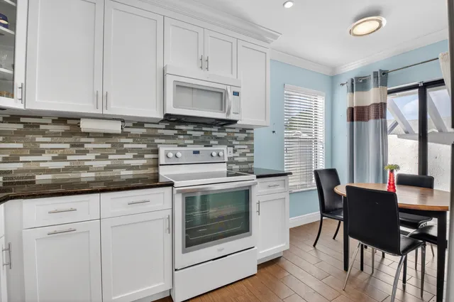 a kitchen with granite countertop white cabinets and white appliances