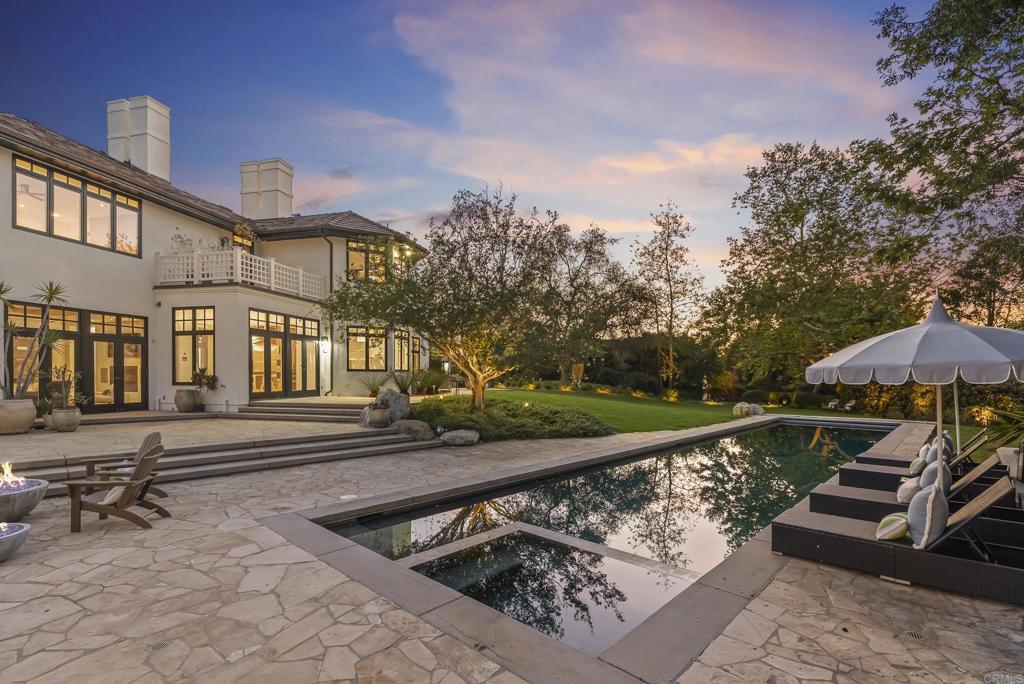 7891 Muirfield Way Rancho Santa Fe, CA 92067 - Photo 24 of 26 a view of a roof deck with table and chairs under an umbrella with large trees