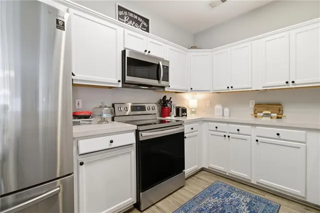 a kitchen with stainless steel appliances granite countertop white cabinets sink and a microwave