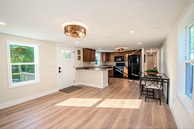 a view of kitchen with stainless steel appliances granite countertop a stove top oven a sink dishwasher and a microwave oven with wooden floor