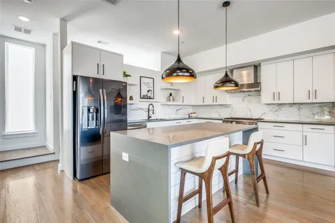 a kitchen with stainless steel appliances granite countertop a sink a window and chairs
