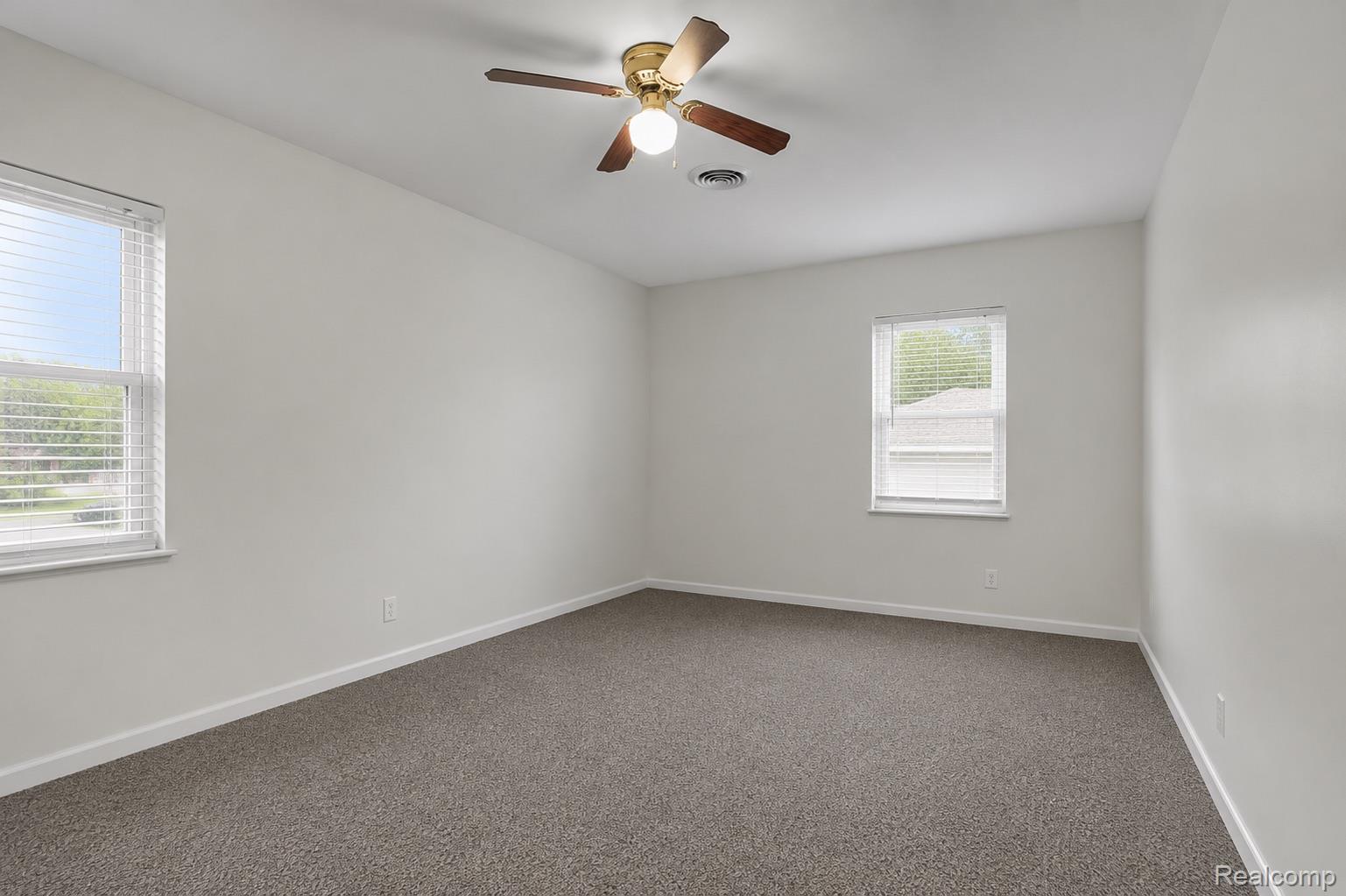 5223 Allen Road Allen Park, MI 48101 - Photo 12 of 12 Spacious room featuring neutral carpet, white walls, two windows with blinds, and a ceiling fan with integrated lighting