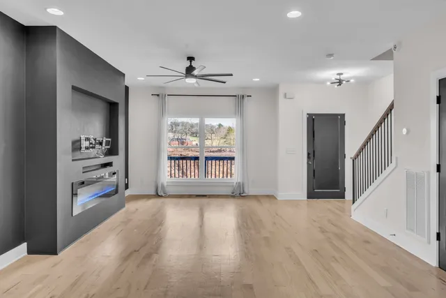 a view of an empty room with a window and wooden floor
