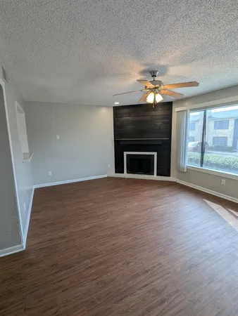 an empty room with wooden floor fireplace and windows