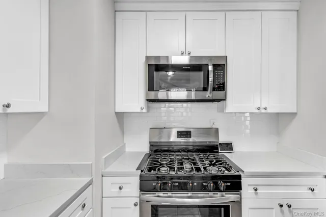 a kitchen with white cabinets and appliances