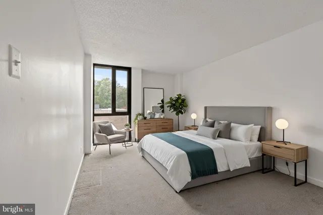 a bedroom with a bed lamp and large window