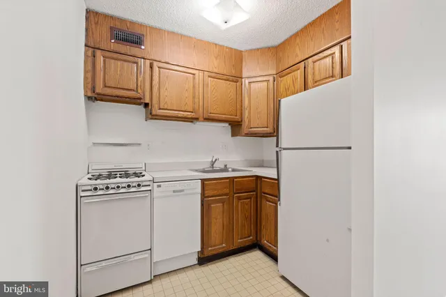 a kitchen with stainless steel appliances granite countertop a refrigerator a stove a sink and dishwasher
