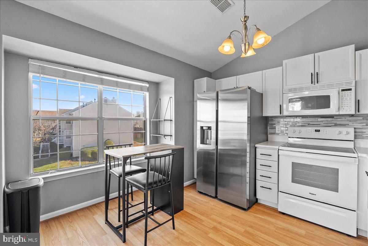 7930 Minor Hill Road Manassas, VA 20109 - Photo 9 of 26 a kitchen with stainless steel appliances granite countertop a stove a refrigerator a microwave a dining table and chairs with wooden floor