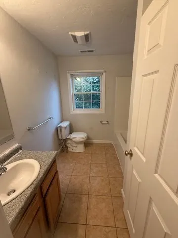 a bathroom with a granite countertop sink mirror vanity and a toilet