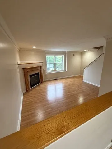a view of empty room with wooden floor and fireplace